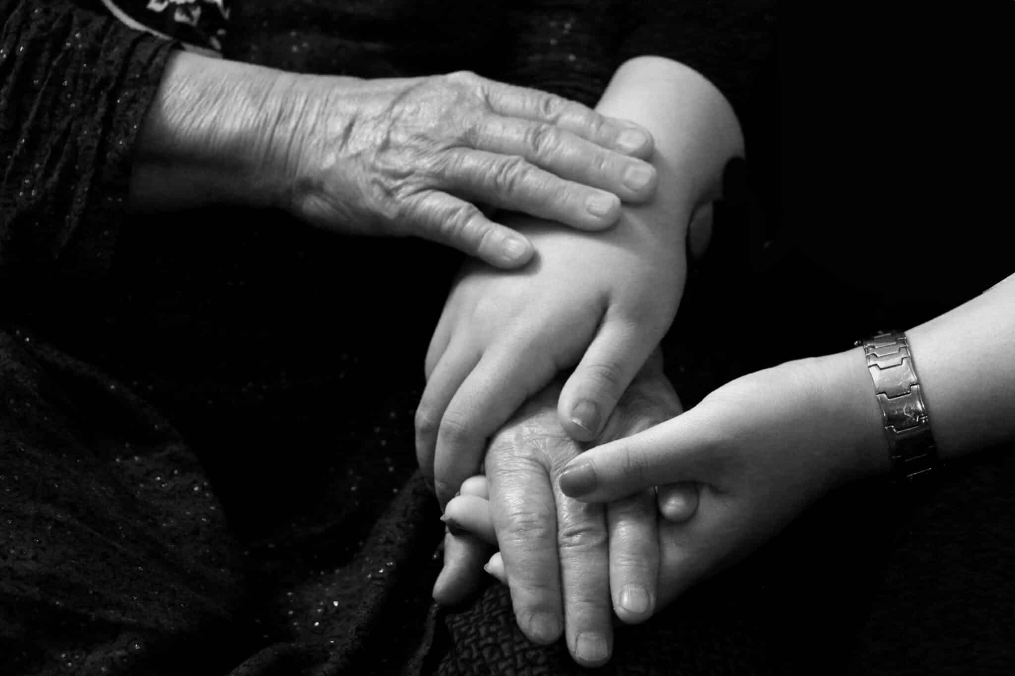 Trois générations de mains réunies, symbole du soutien familial après un décès